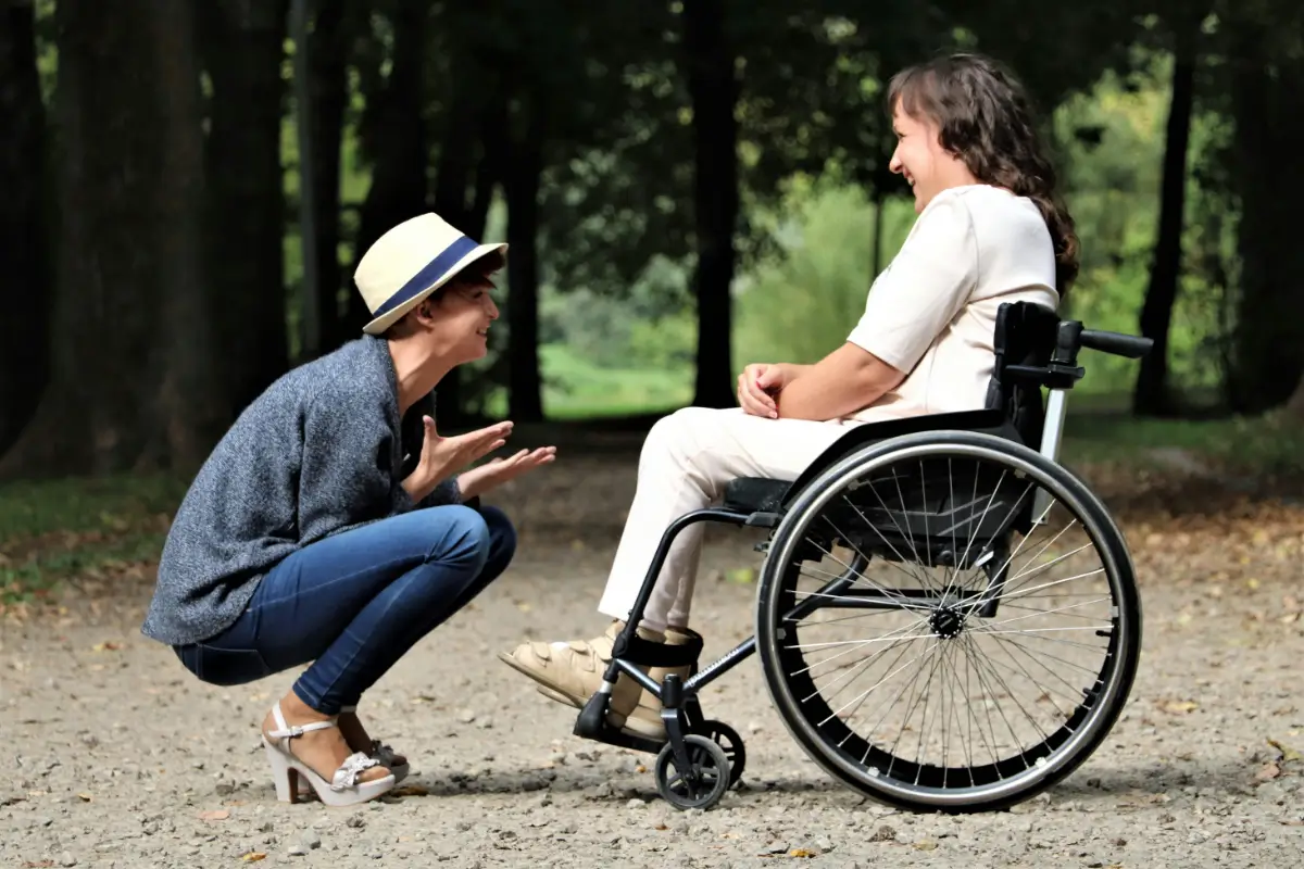 A woman in blue jeans and white shirt sitting on the ground next to a man.