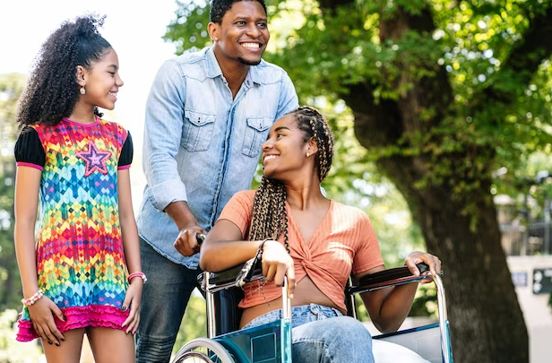 A man in a wheelchair with two women and a girl.